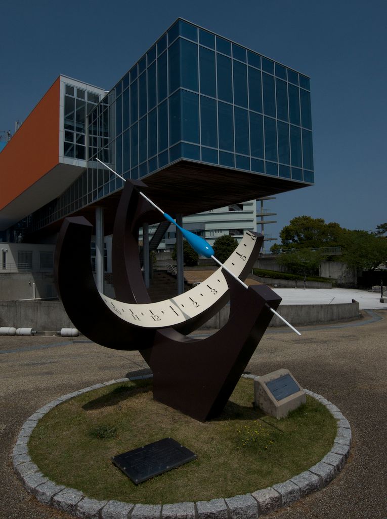 Sundial at Sakamoto Ryoma Memorial Museum. A contemporary sundial accents the ultra modern architectural design of Sakamoto Ryoma Memorial Museum at Katsurahama Beach in Kochi. On an adjacent hilltop, the crumbled remains of Urado Castle are barely detectable due to extreme weathering. 