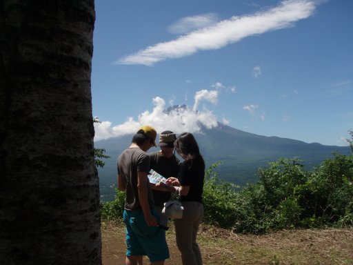 Trio on Mount Tenjo check map as cloud swirl around Mount Fuji near Kawaguchiko Japan.