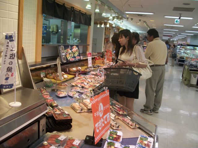 Meat is somewhat expensive in Japan, but still very popular in moderate amounts. These shoppers are looking over selections in the meat section of a supermarket located in a department store basement in Wakayama Japan. Wakayama is a quiet city located on the Kii peninsula on the east edge of the Inland Sea. While the Wakaura Bay of Wakayama is one of the most beautiful seasides in Japan, Wakayama remains largely undiscovered outside of Japan.