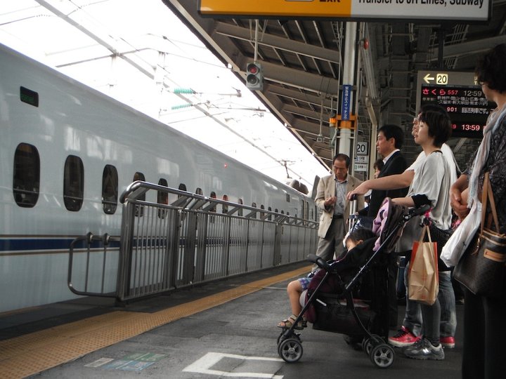 Parents with a child in a stroller wait for the Shinkansen to load in Shin-Osaka Station.