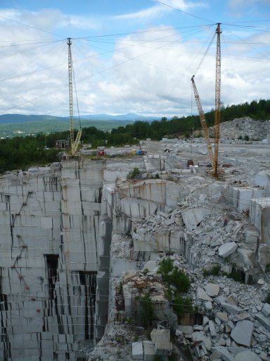 At the time of this photo, the E. L. Smith Quarry in Graniteville, South Barre, Vermont, USA, had two derricks for removing granite and transporting stone workers. On the wall at the left of the photo are ladders providing an exit for the workers should power to the derricks fail.