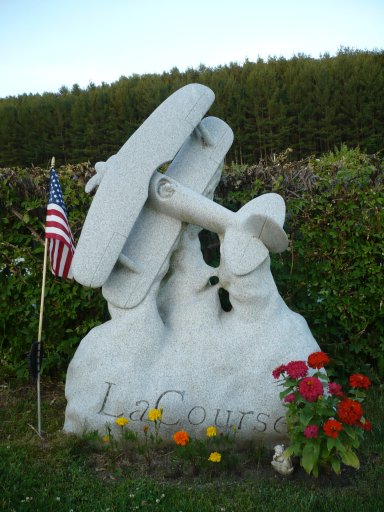 The grave of a pilot named LaCourse is located in the Hope Cemetery in Barre, Vermont. The bi-plane has broken through the clouds. The American flag rests in a stand available only for veterans of the US military.