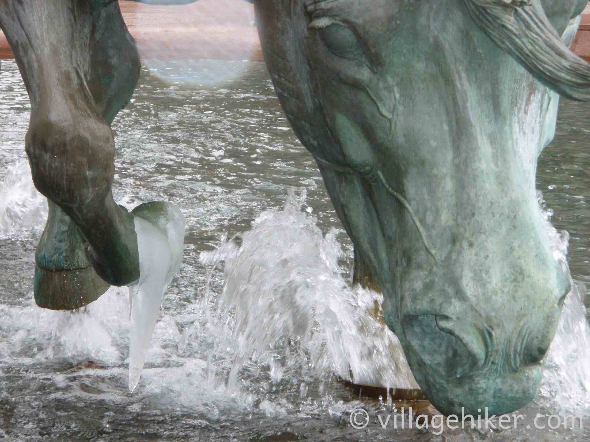 bronze mustangs splash through the fountain in a heavy rain.