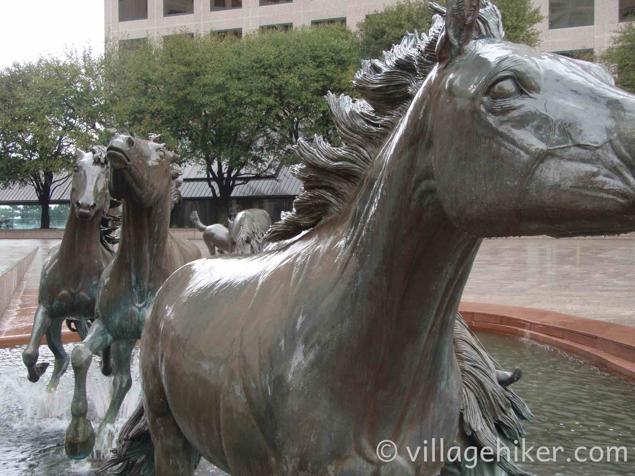 bronze mustangs splash through the fountain in a heavy rain.