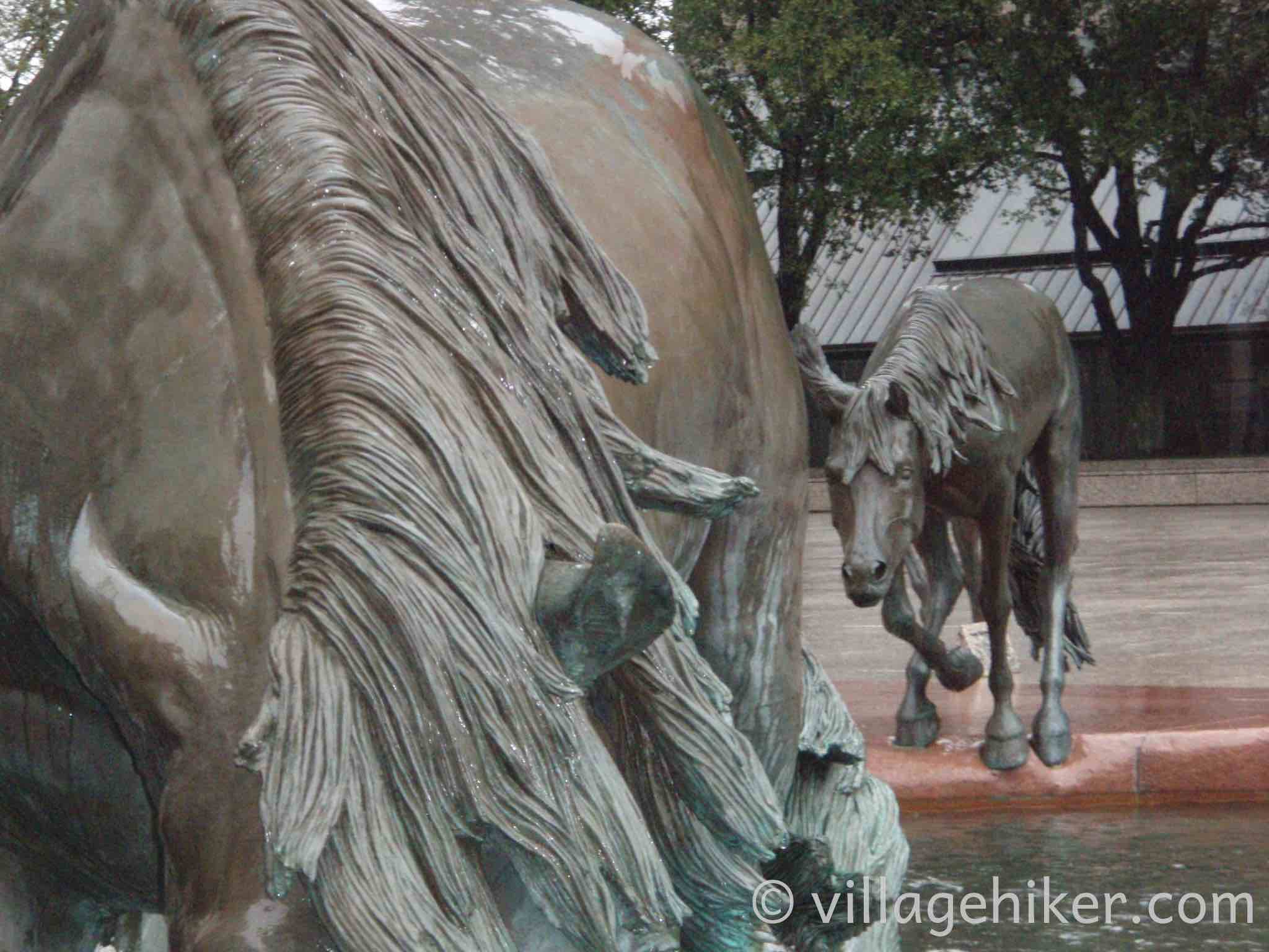 bronze mustangs splash through the fountain in a heavy rain.