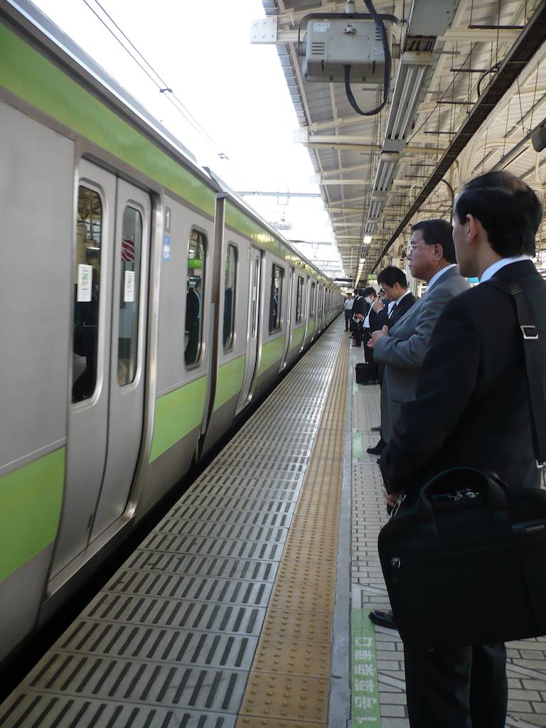 Japanese Businessmen Wait for Train to Stop